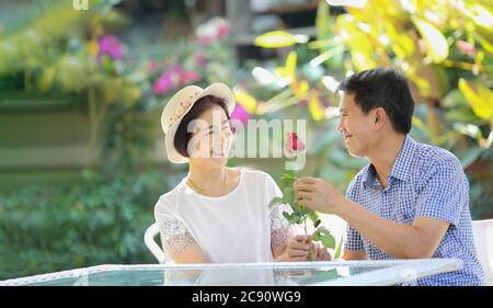 L'uomo di mezza età asiatico dà una rosa alla moglie in giorno di San Valentino Foto Stock