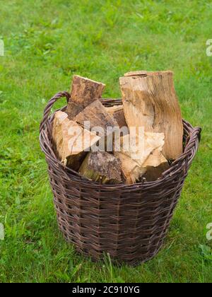 cesto di vimini pieno di legno tritato su sfondo verde erba Foto Stock