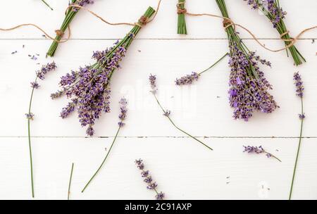 Fiori freschi di lavanda e bouquet sono essiccati su sfondo di legno bianco. Mazzi di fiori di lavanda secco. Erbe aromaterapiche per aromaterapia alla lavanda Foto Stock