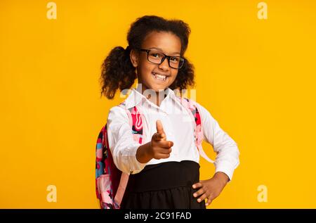 Happy African American Schoolgirl che punta il dito alla fotocamera in Studio Foto Stock