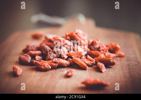 Bacche di goji su un tagliere di legno Foto Stock