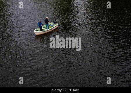 Due uomini pescano da una piccola barca, due pescatori su una barca Foto Stock