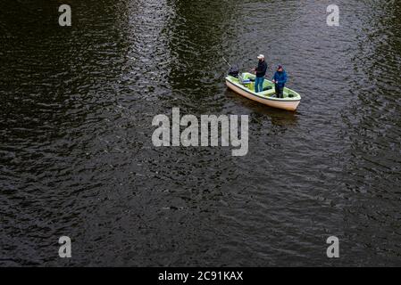 Due uomini pescano da una piccola barca, due pescatori su una barca Foto Stock