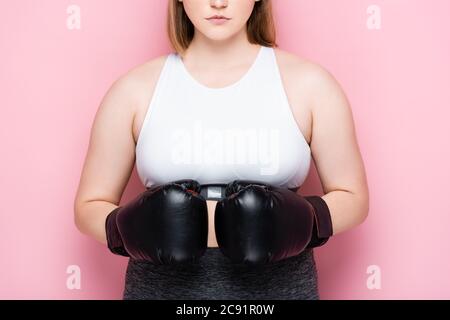 vista ritagliata della taglia più ragazza in bianco top e guanti di boxe su rosa Foto Stock
