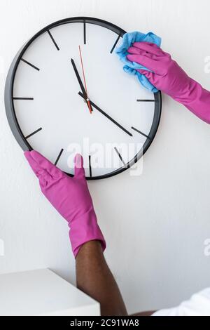 Vista ritagliata dell'orologio per la pulizia afroamericano sulla parete in ufficio Foto Stock