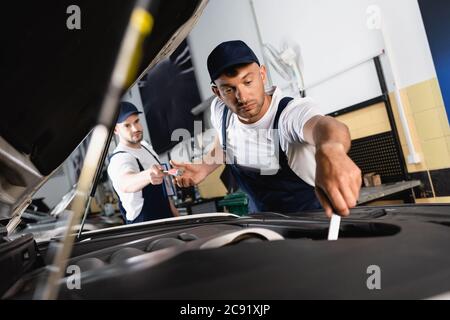 fuoco selettivo del meccanico nel tappo che dà il cacciavite al collega che manchi la riparazione della vettura in officina Foto Stock