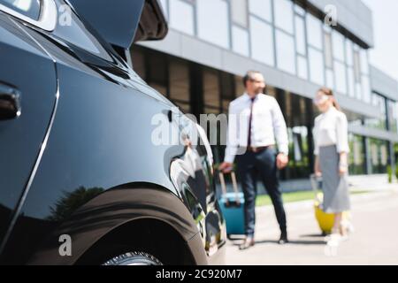 Il punto di interesse è la scelta di una coppia di lavoro che cammina con i bagagli in auto sulla strada urbana Foto Stock