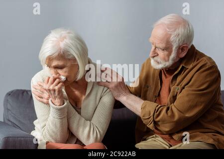 uomo anziano calmando moglie piangendo mentre tocca la sua spalla Foto Stock