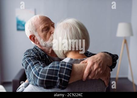 uomo anziano abbracciando e baciando moglie, che soffre di malattia di alzheimer Foto Stock