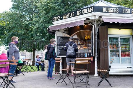 Edimburgo, Scozia, Regno Unito. 28 Luglio 2020. Poiché l'allentamento delle restrizioni di blocco del Coronavirus Covid-19 un numero crescente di visitatori inizia a riunirsi presso il caffè all'aperto e i tavoli in East Princes Street Gardens. Coda a distanza sociale presso il chiosco bar. Credit: Craig Brown/Alamy Live News Foto Stock