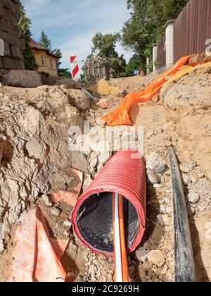 I cavi fuoriescono dal tubo di sicurezza scanalato in strada, dettaglio di uno scavo. Internet e società di fornitori di dati che costruiscono il conne pshychical Foto Stock