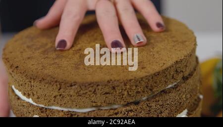 Passo dopo passo. Ragazza che monta una torta al cioccolato con crema di burro brillante e colorata Foto Stock