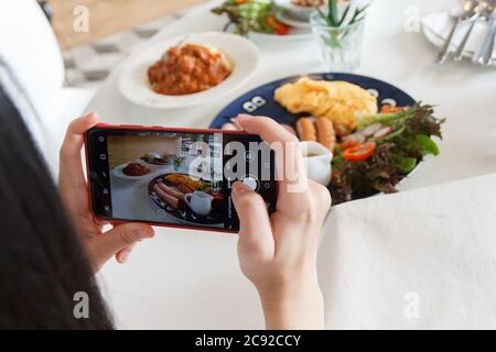 12 luglio 2020 - Khaoyai Thailandia : mani con il telefono primo piano immagini della colazione. Foto Stock