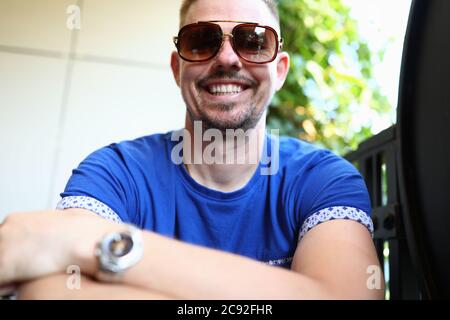 L'uomo in occhiali da sole si siede e sorride closeup Foto Stock