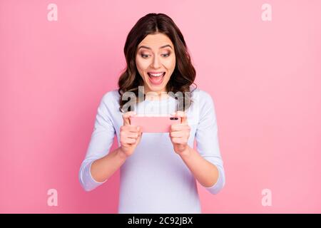 Foto di bella signora attraente tenere le mani del telefono rimanere a casa tempo di quarantena giocare online video gioco eccitato buon umore wear camicia bianca casual Foto Stock