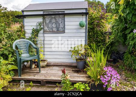 Capanna giardino in un giardino locale, con un sedile estivo in plastica all'esterno, Kilwinning, Ayrshire, Scozia, Regno Unito Foto Stock