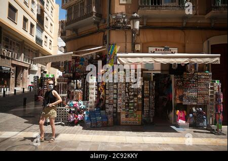 Malaga, Spagna. 28 luglio 2020. Un turista che indossa una maschera facciale come precauzione visto fuori di un negozio di souvenir nel centro città.il governo del Regno Unito ha imposto una quarantena a tutti i turisti che viaggiano dalla Spagna a causa dei suoi alti livelli di casi COVID-19, mentre la Germania non consiglia di viaggiare in alcune regioni della Spagna. Il settore turistico della Costa del Sol in Andalusia è il più colpito dalla decisione del Regno Unito che coincide con la sessione estiva. Il turismo britannico rappresenta l'investimento più straniero a Malaga. Credit: Jesus Merida/SOPA Images/ZUMA Wire/Alamy Live News Foto Stock