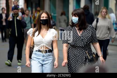 Due giovani donne, indossando maschere per strada, postlock down, a Nottingham. Foto Stock
