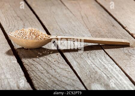 Il cucchiaio di legno riempito di grano su tavole di grano. Foto Stock