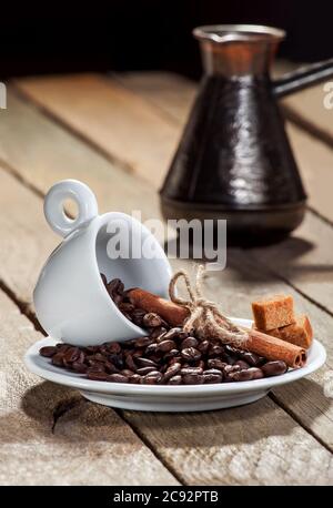 Piatto con una tazza per espresso e cereali caffè e cannella contro il caffè su un tavolo di legno. Foto Stock