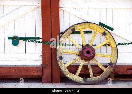 la ruota del carrello di legno costa vicino al cancello di legno. Foto Stock