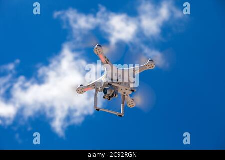 Quad copter drone bianco con fotocamera digitale ad alta risoluzione che vola nel cielo blu. Foto Stock