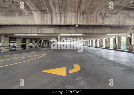 Garage vuoto con linee gialle per parcheggi e frecce direzionali gialle. Foto Stock