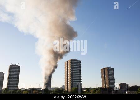 Il fumo sorge dal fuoco alla Grenfell Tower, un blocco di appartamenti a 24 piani parte della Lancaster West Estate a North Kensington, Londra, Regno Unito. Il fuoco è stato avviato la mattina presto da un frigorifero-congelatore difettoso al quarto piano. Si diffonde rapidamente sull'esterno dell'edificio, attraverso il rivestimento esterno e l'isolamento. L'incendio causò 72 morti, comprese quelle di due vittime che poi morirono in ospedale. Oltre 70 persone sono rimaste ferite e 223 sono fuggite. È stato il più letale incendio strutturale del Regno Unito dal 1988 e il peggiore incendio residenziale britannico dalla seconda guerra mondiale Foto Stock