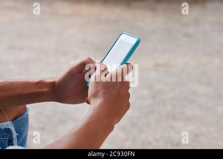 Primo piano di un giovane che scrive un massaggio nel suo telefono Foto Stock