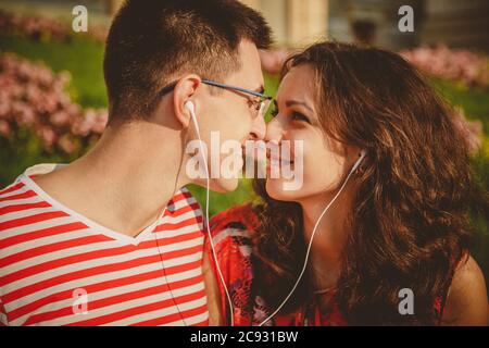Giovane giovane giovane giovane adolescente con auricolari che ascoltano la musica seduto nel parco Foto Stock