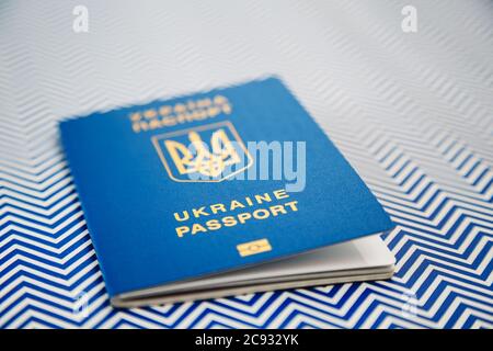 Nuovo passaporto biometrico internazionale blu ucraino con chip di identificazione su sfondo bianco e blu. Messa a fuoco selettiva Foto Stock