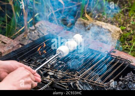 whote marshmallows su spiedino sopra il fuoco all'aperto Foto Stock