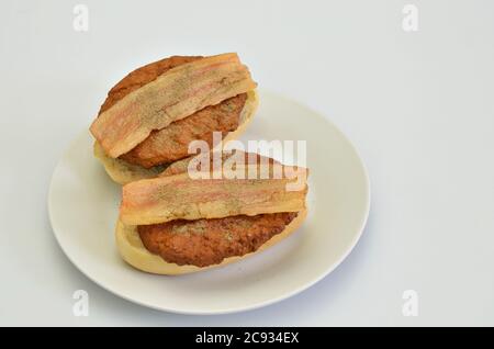 due panini con manzo e pancetta su piatto bianco, guardaroba, isolati su sfondo bianco Foto Stock