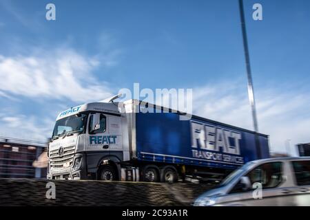 Reagire il trasporto Mercedes-Benz Actros curtainsider carrello guida su un urbano a doppia carreggiata Foto Stock