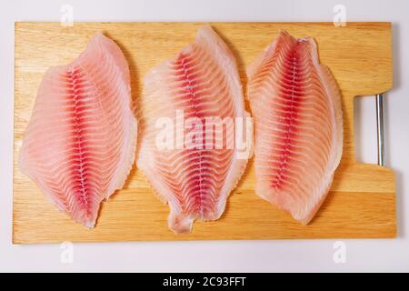 Primo piano di filetto fresco crudo di pesce tilapia, colpo d'asta Foto Stock