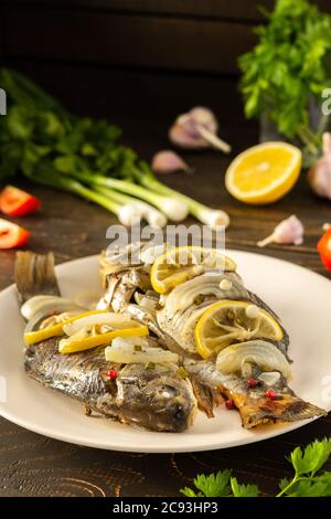 Carassius al forno al forno con limone e spezie in lamina, carpa crogiana di pesce di fiume cotta Foto Stock