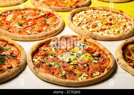 Circoli di pizza con carne, uova, pomodori e formaggio su sfondo ligneo. Pizza e pizzeria italiana. Menu con pizza diversa. Togliere il cibo con vari ingredienti e bordi croccanti Foto Stock