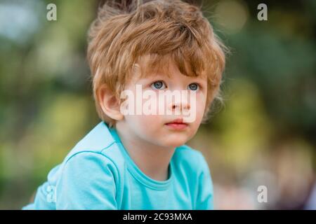 ritratto di un ragazzo felice in estate. Ragazzo di due anni in T-shirt blu sorridente in estate su una passeggiata Foto Stock