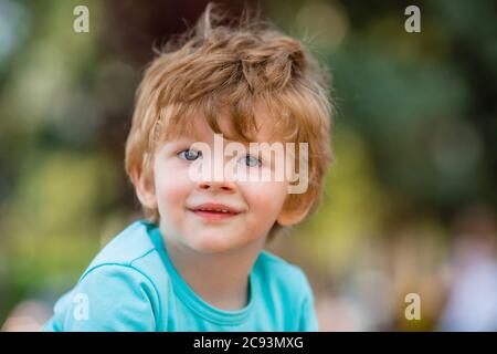 ritratto di un ragazzo felice in estate. Ragazzo di due anni in T-shirt blu sorridente in estate su una passeggiata Foto Stock