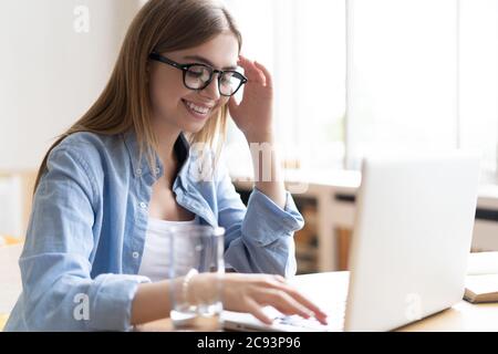 Lavorare a casa mi consente di lavorare in modo flessibile. Piacevole felice giovane donna freelance che lavora sul computer a casa. Foto Stock