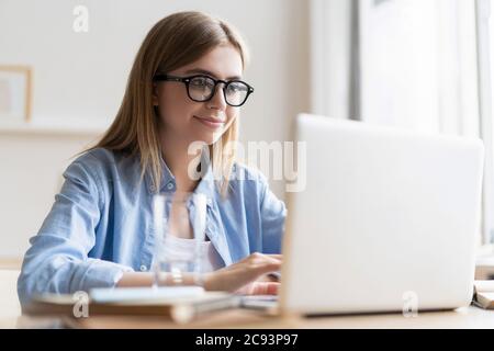 Lavorare a casa mi consente di lavorare in modo flessibile. Piacevole felice giovane donna freelance che lavora sul computer a casa. Foto Stock