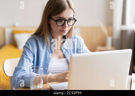 Lavorare a casa mi consente di lavorare in modo flessibile. Piacevole felice giovane donna freelance che lavora sul computer a casa. Foto Stock