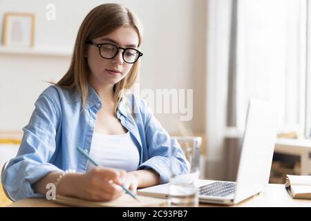 Lavorare a casa mi consente di lavorare in modo flessibile. Piacevole felice giovane donna freelance che lavora sul computer a casa. Foto Stock