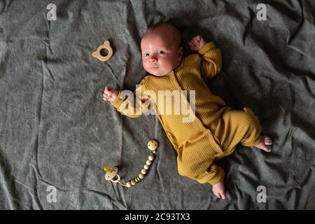 Un mese neonato con gli occhi aperti giace sulla schiena su sfondo grigio. Primo piano ritratto di carino ragazzino. Foto Stock