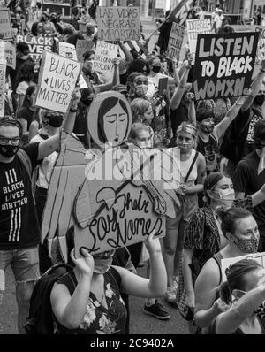 Black Womens/Womxn March Black Lives Matter protesta - Marching persone con potenti segni. Angeli e ascoltare donne nere Foto Stock