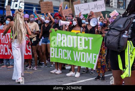 Black Womens/Womxn March Black Lives Matter protesta - Banner Protect Black Women tenuto di fronte alla folla di protesta Foto Stock