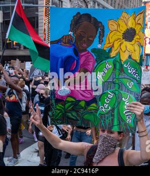 Black Womens/Womxn March Black Lives Matter protesta - Black girl annaffiatura fiori segno con bandiera Foto Stock