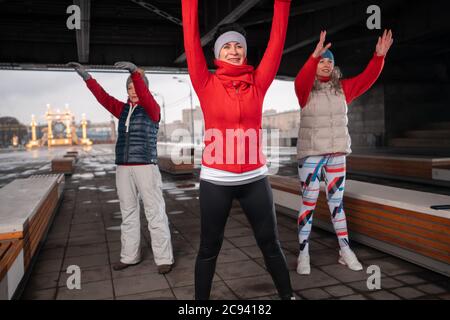 Adulti più anziani attivi nello sport e nel fitness. Donne di mezza età che si esercitano all'aperto nel parco. Sei piedi di spazio sociale a distanza tra gli individui Foto Stock