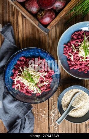 Gnocchi di barbabietola bolliti saporiti, ricoperti di hummus, tofu affumicato e erba cipollina Foto Stock