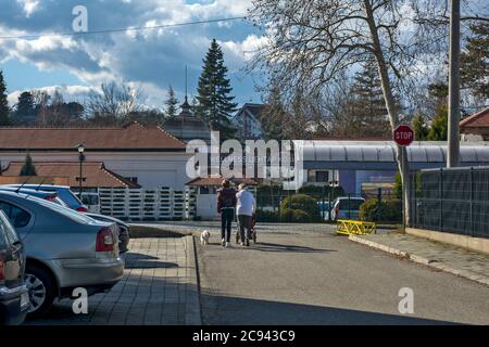 Banja Koviljača, Serbia, 15 febbraio 2020. Famiglia in una passeggiata di fronte al centro benessere. Portano un uomo in sedia a rotelle alla terapia. La cura termale Foto Stock